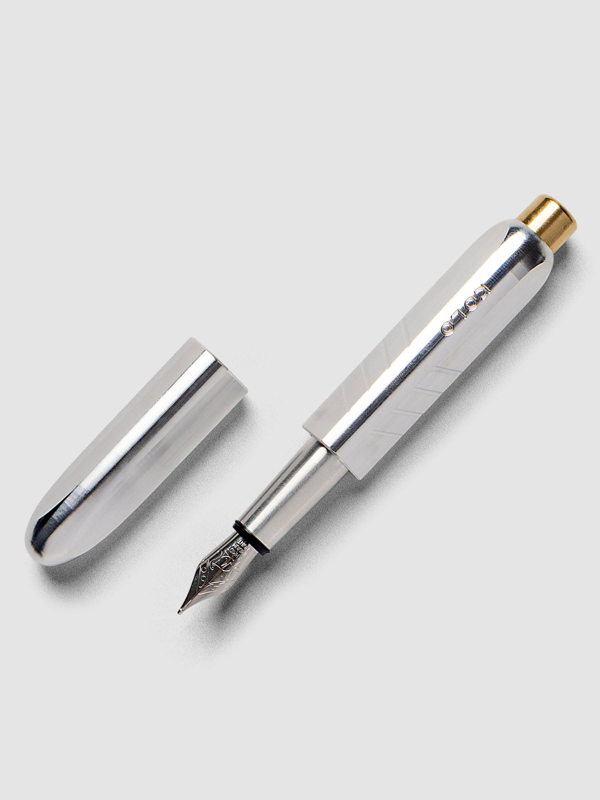 Kolo Tino Fountain Pen in the color Raw Aluminum, a silver toned metal barrel with brass accents and a silver medium nib shown with cap off.