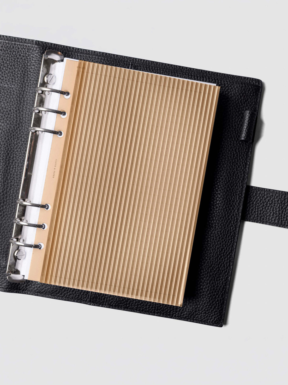 Bisque fluted planner dashboard in A5 size shown in a black leather six ring agenda with silver rings.