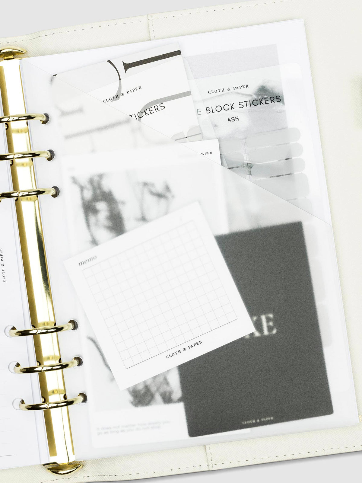 Folder in use inside a white leather agenda. The folder contains an assortment of journaling cards, stickers, and sticky notes.