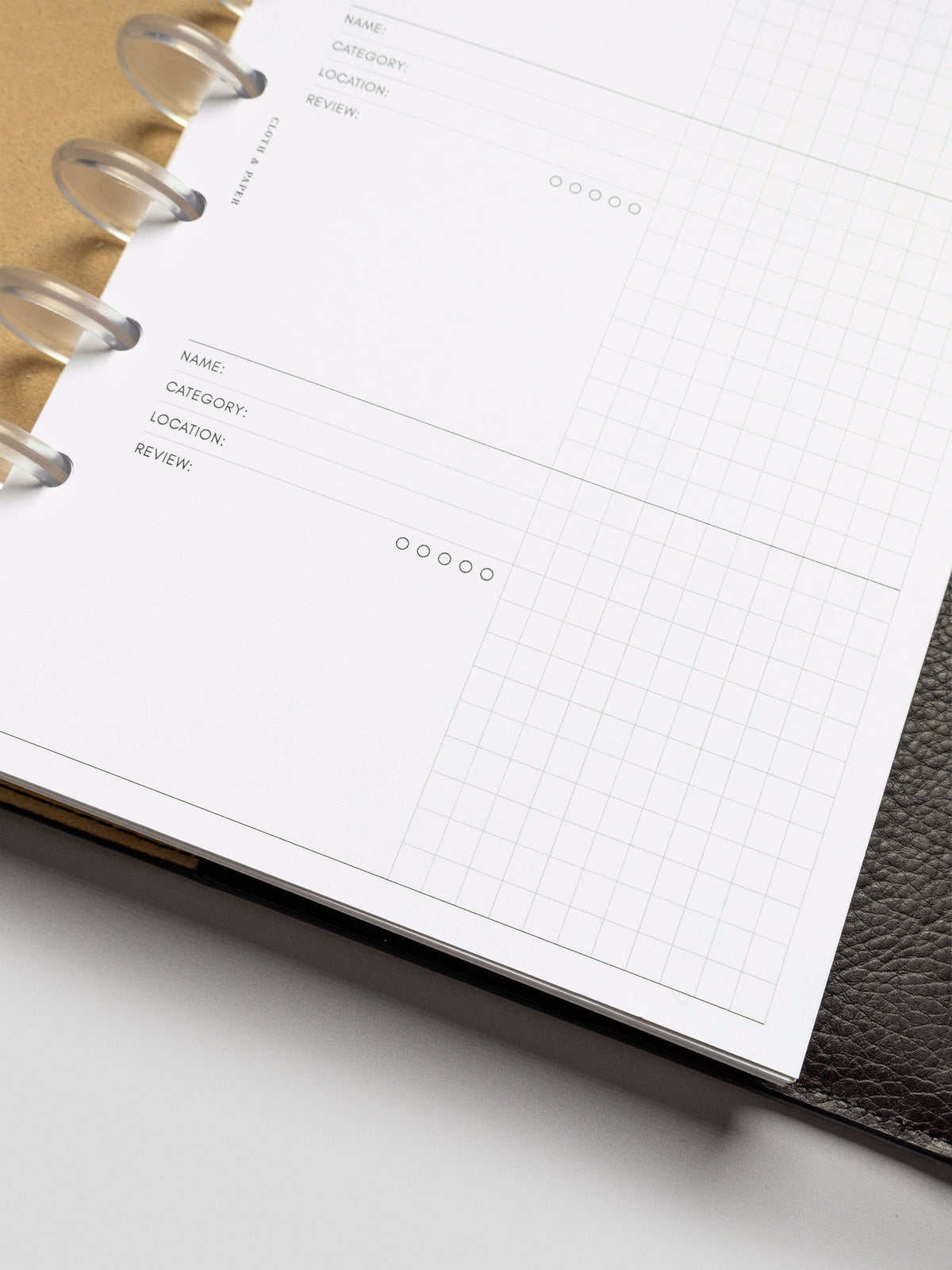 Bottom angle detail of the Experience Tracker Insert in a Half Letter planner, focusing on the layout of the lower two entries and the frosted disc binding.