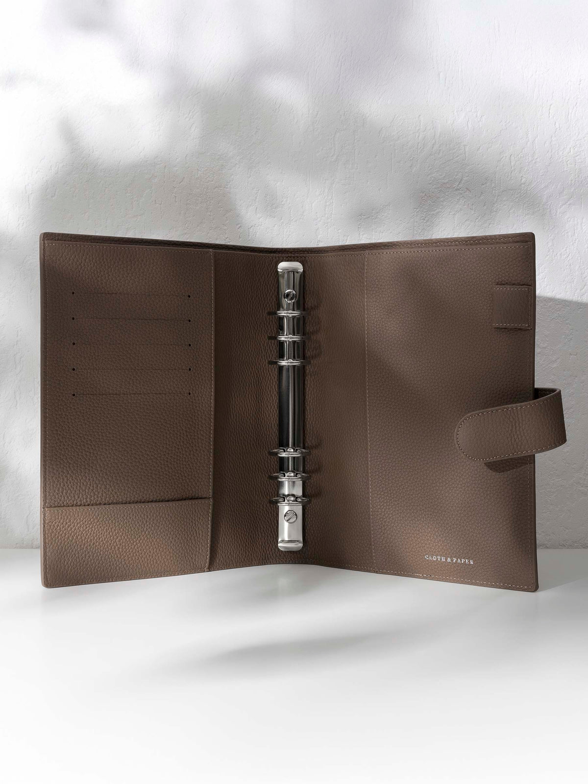 Cortado leather agenda displayed against a shadowed background. It is opened to display the silver hardware and company foil stamp.