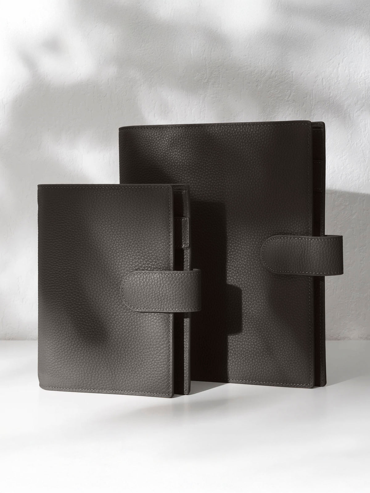 Two cafenoir leather agendas on an off-white background.