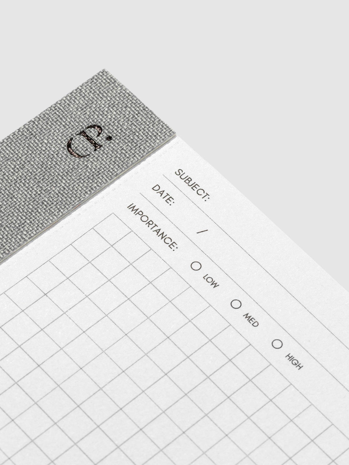 Closeup of the top left corner of the notepad. The Cloth and Paper CP logo is visible alongside the subject, date, and importance headers on the notepad.