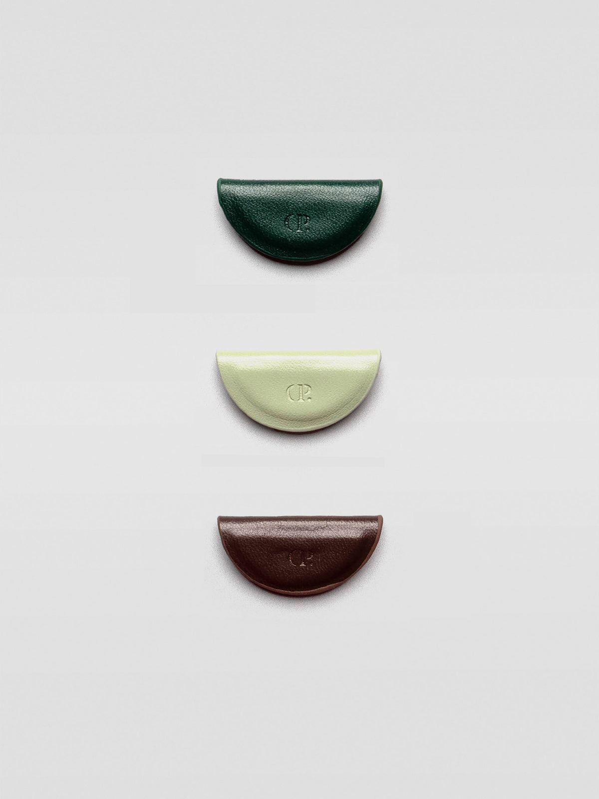 Three half-moon magnetic bookmarks in dark green, pale mint, and deep brown arranged vertically