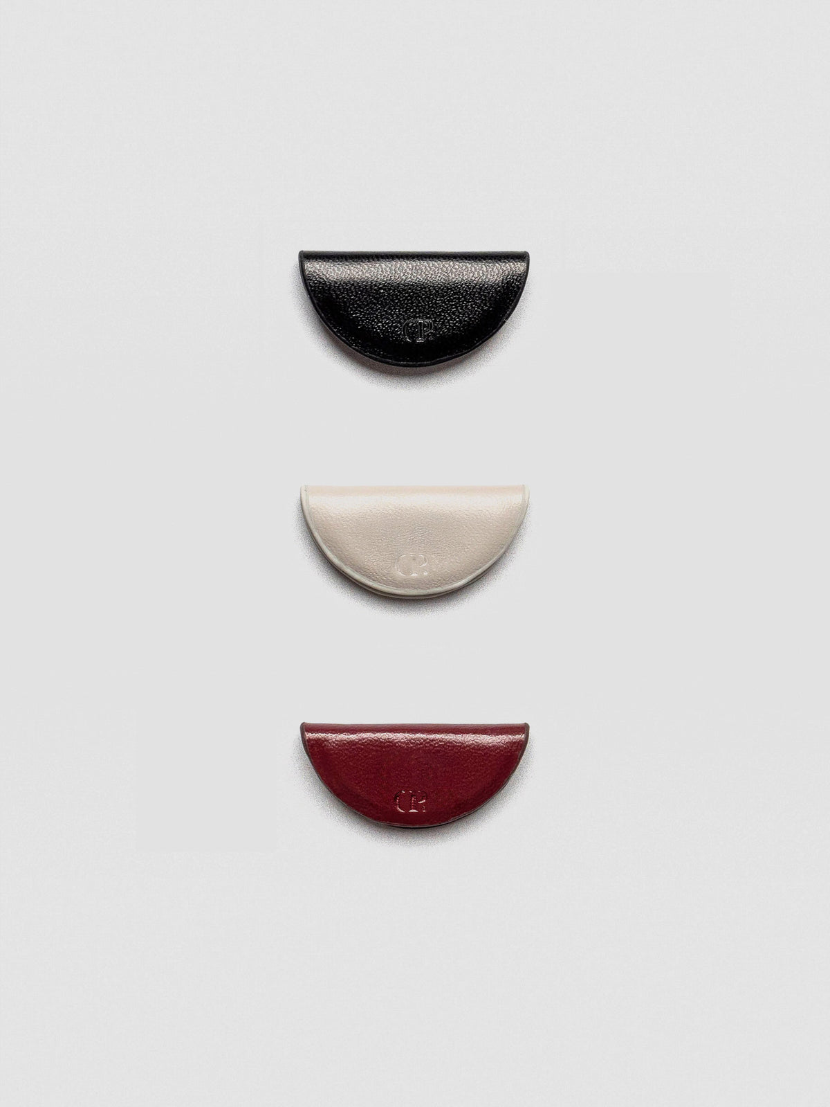 A set of three semi-circle leather magnetic bookmarks in black, cream, and burgundy colors
