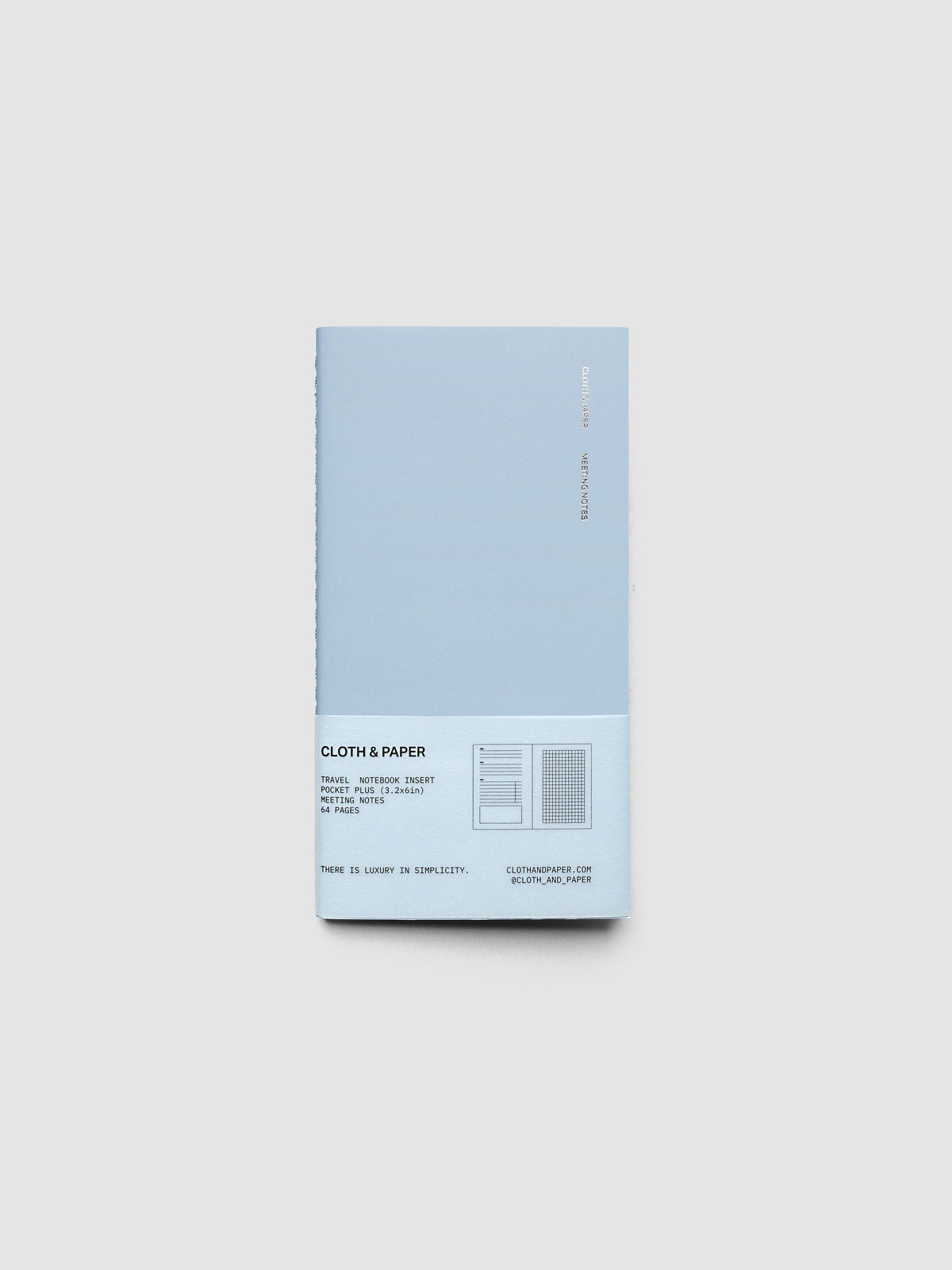 A light blue cloth and paper notebook with a vellum label at the bottom, shown on a neutral light gray background.
