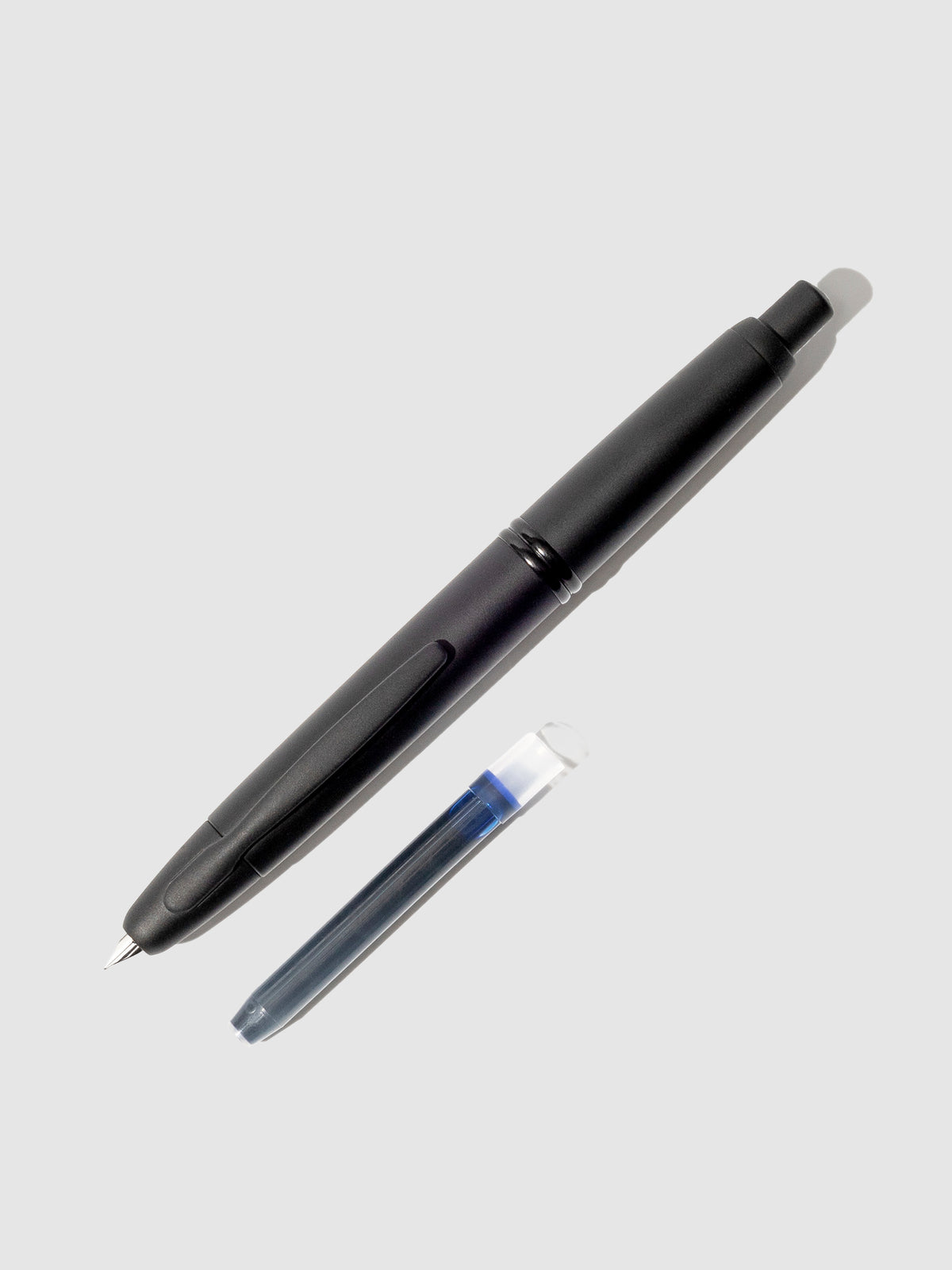 Pilot Vanishing Point fountain pen displayed next to a blue black ink cartridge on a neutral background.
