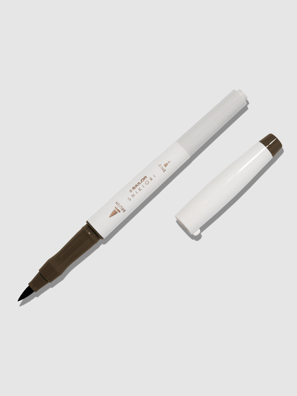 Brush pen displayed on a neutral background. It is uncapped with its brush nib exposed, and the cap lying parallel to the marker. Color pictured is Doyou. 