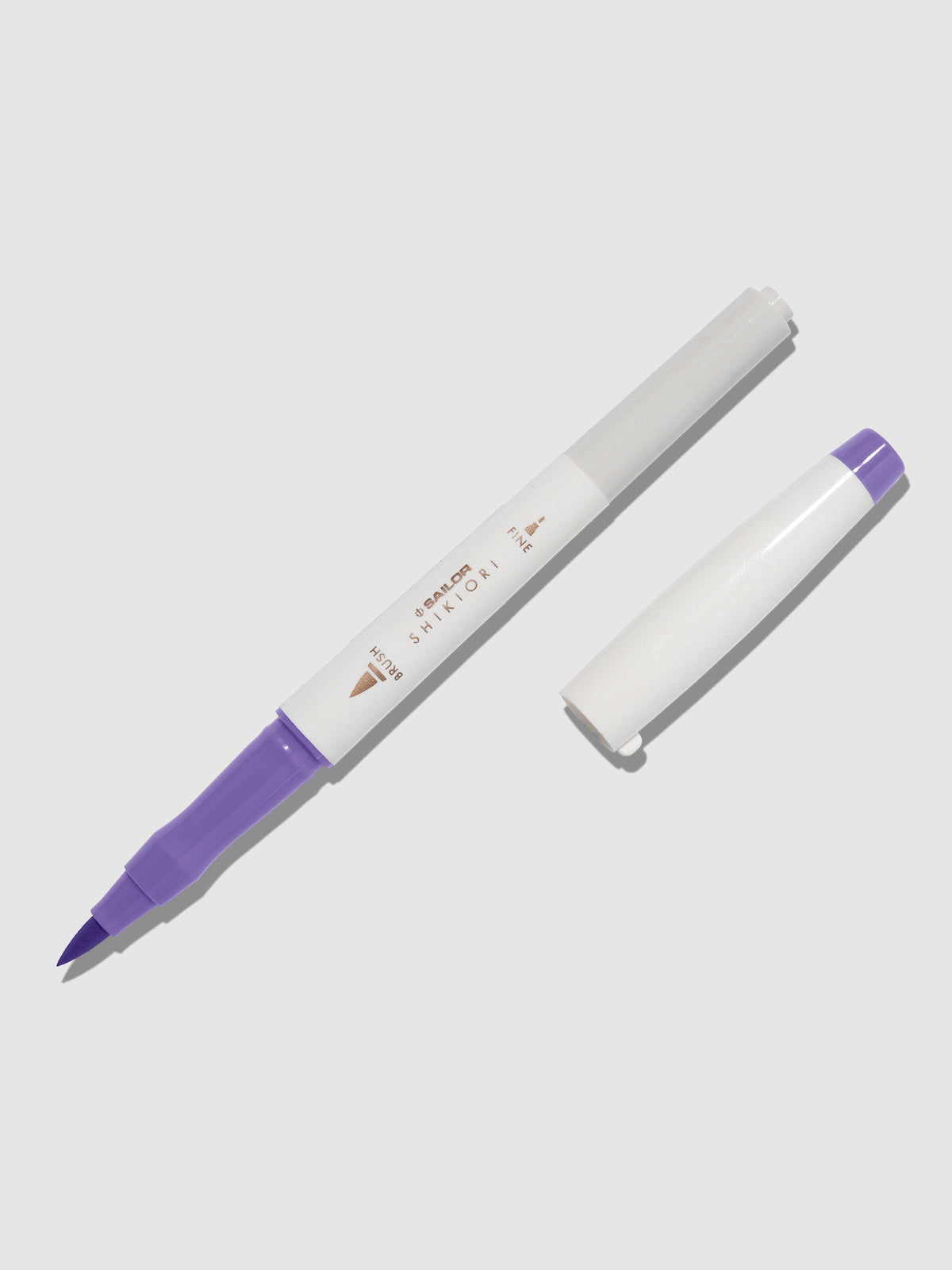 Brush pen displayed on a neutral background. It is uncapped with its brush nib exposed, and the cap lying parallel to the marker. Color pictured is Fujisugata. 