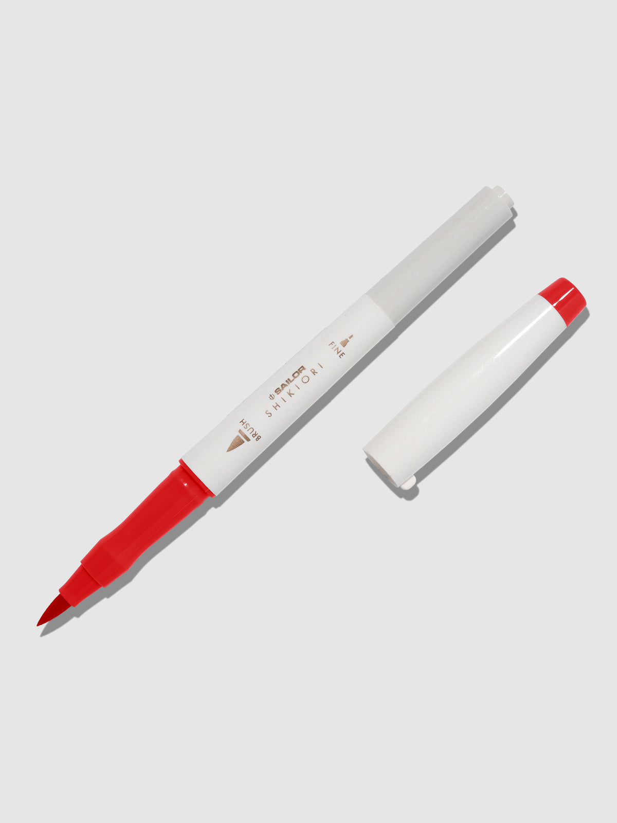 Brush pen displayed on a neutral background. It is uncapped with its brush nib exposed, and the cap lying parallel to the marker. Color pictured is Irori. 