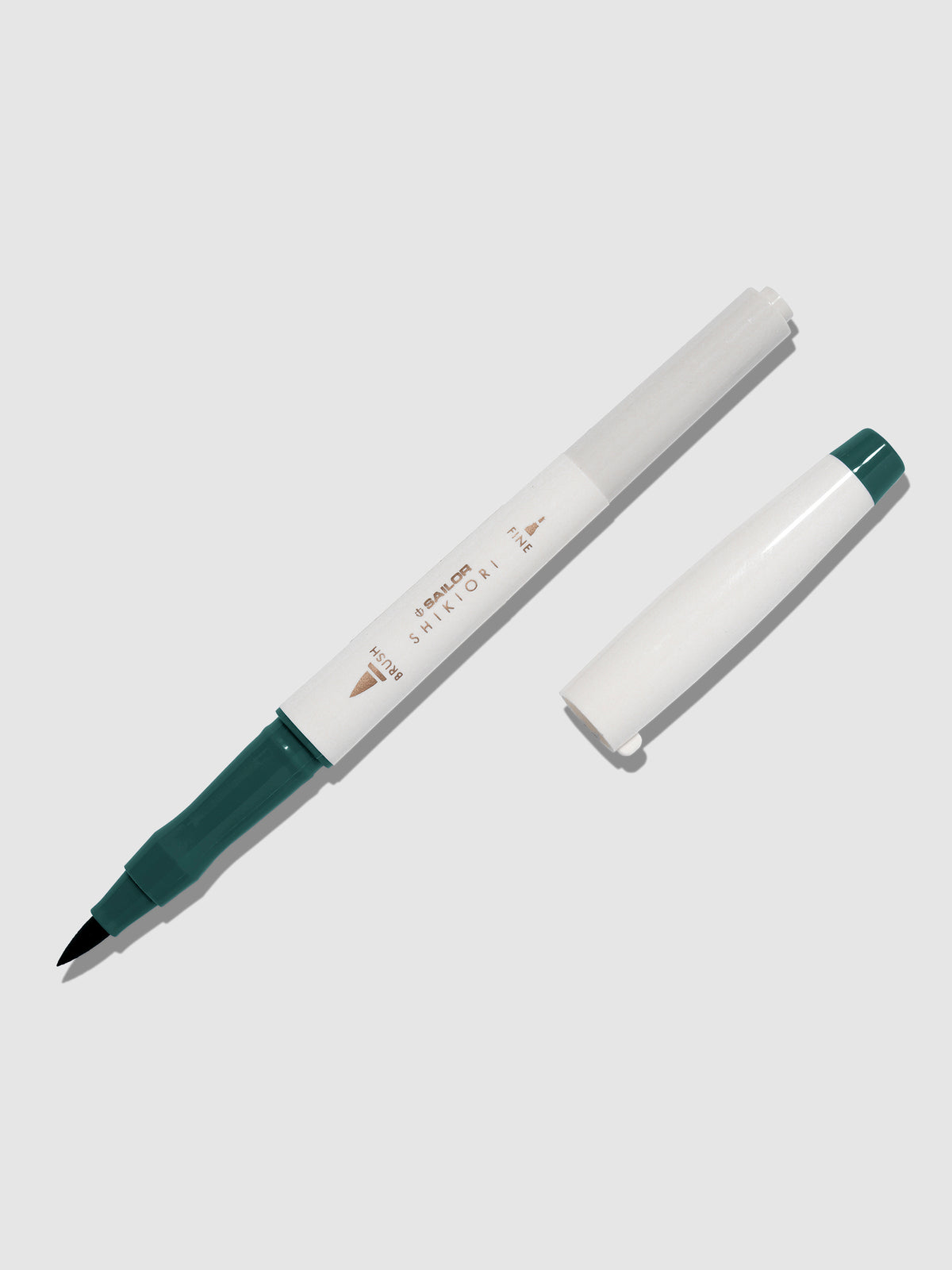 Brush pen displayed on a neutral background. It is uncapped with its brush nib exposed, and the cap lying parallel to the marker. Color pictured is Miruai. 
