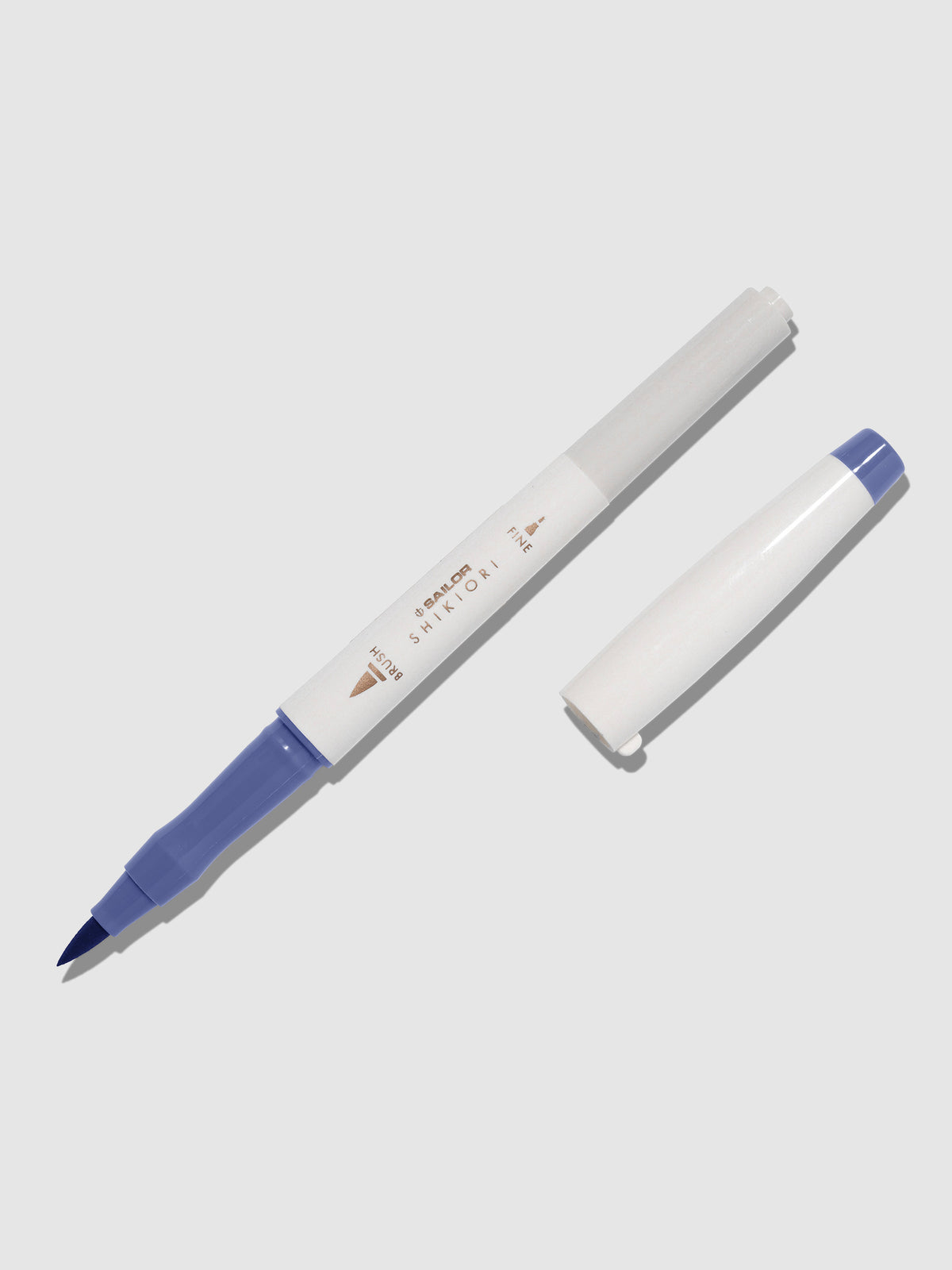 Brush pen displayed on a neutral background. It is uncapped with its brush nib exposed, and the cap lying parallel to the marker. Color pictured is Nioisumire. 