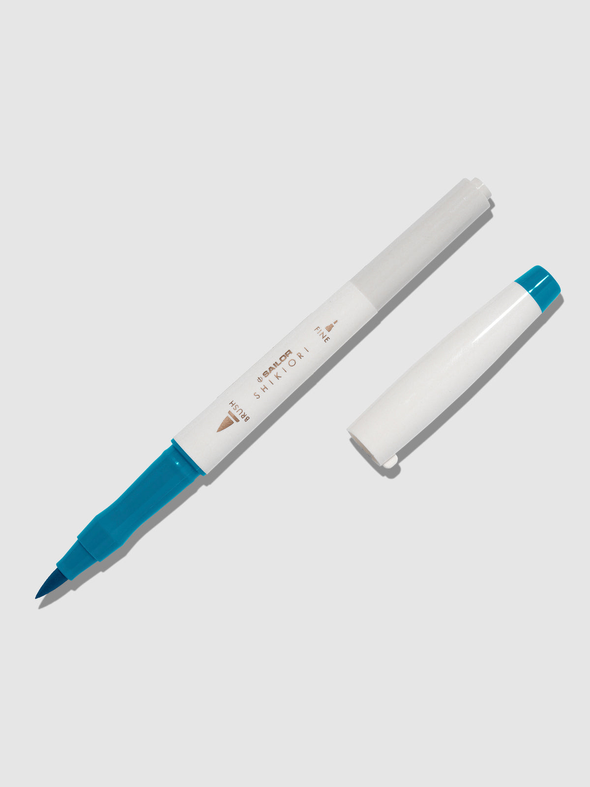 Brush pen displayed on a neutral background. It is uncapped with its brush nib exposed, and the cap lying parallel to the marker. Color pictured is Yamadori. 