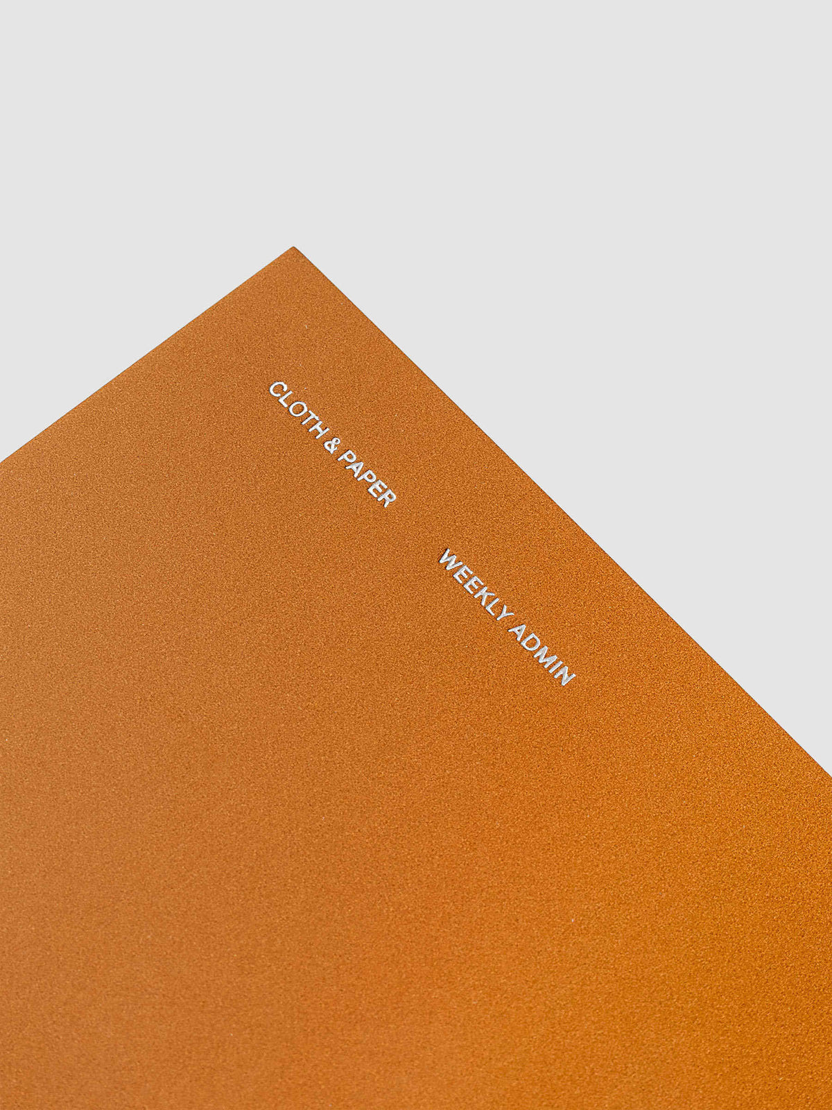 Close up of the top left of the Weekly Admin Pocket Plus travel notebook with silver foil cover text, displayed on a neutral background