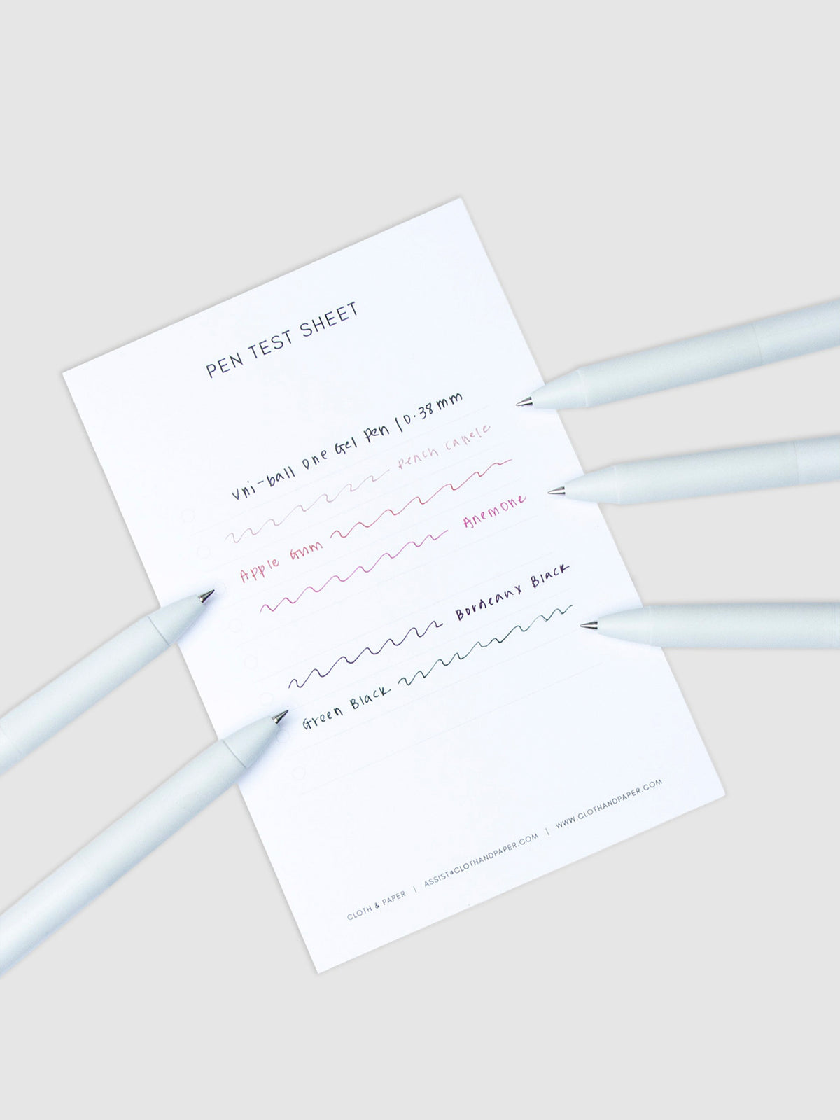 Pen test sheet showing ink samples for Powder Snow, Blue Colon, Denim Blue, Pansy, and Sumire ink. Five pens are resting on the edges of the pen test sheet.