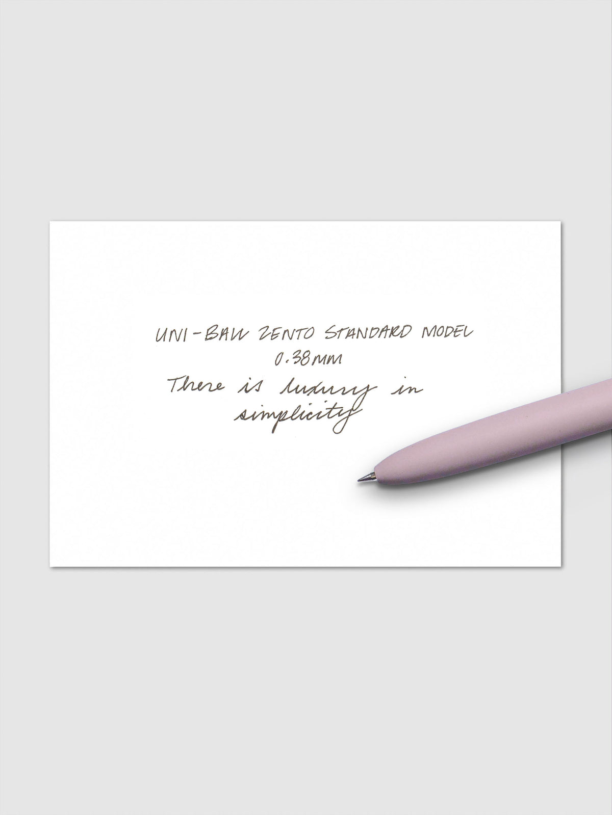 Handwritten sample using the Uni-ball Zento Standard Model Pen with black ink and a 0.38 mm nib. Shown with lavender pen resting across paper.