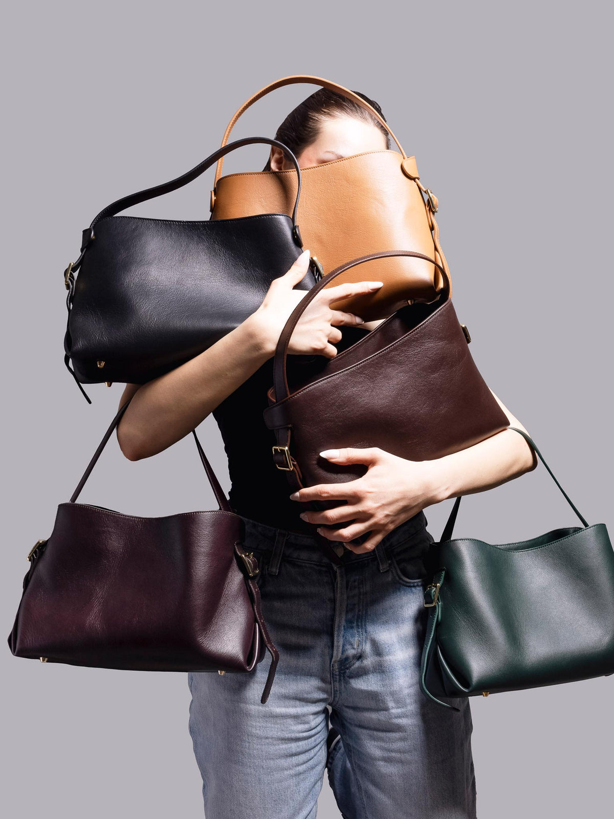 Person holding bags in a variety of shapes and colors.