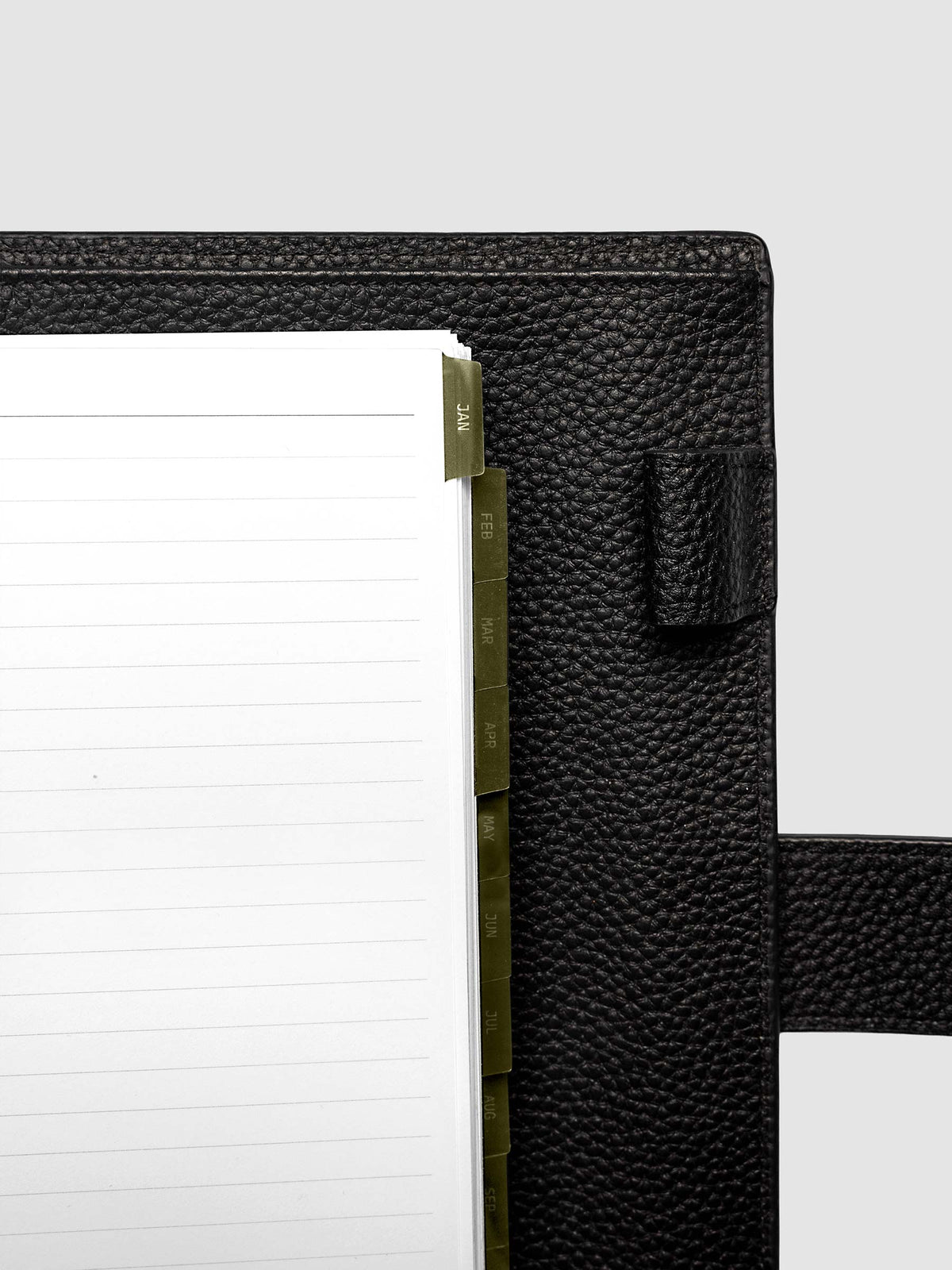 Top right corner close-up of olive green monthly divider in A5 6-Ring Punch planner showing tab label detail