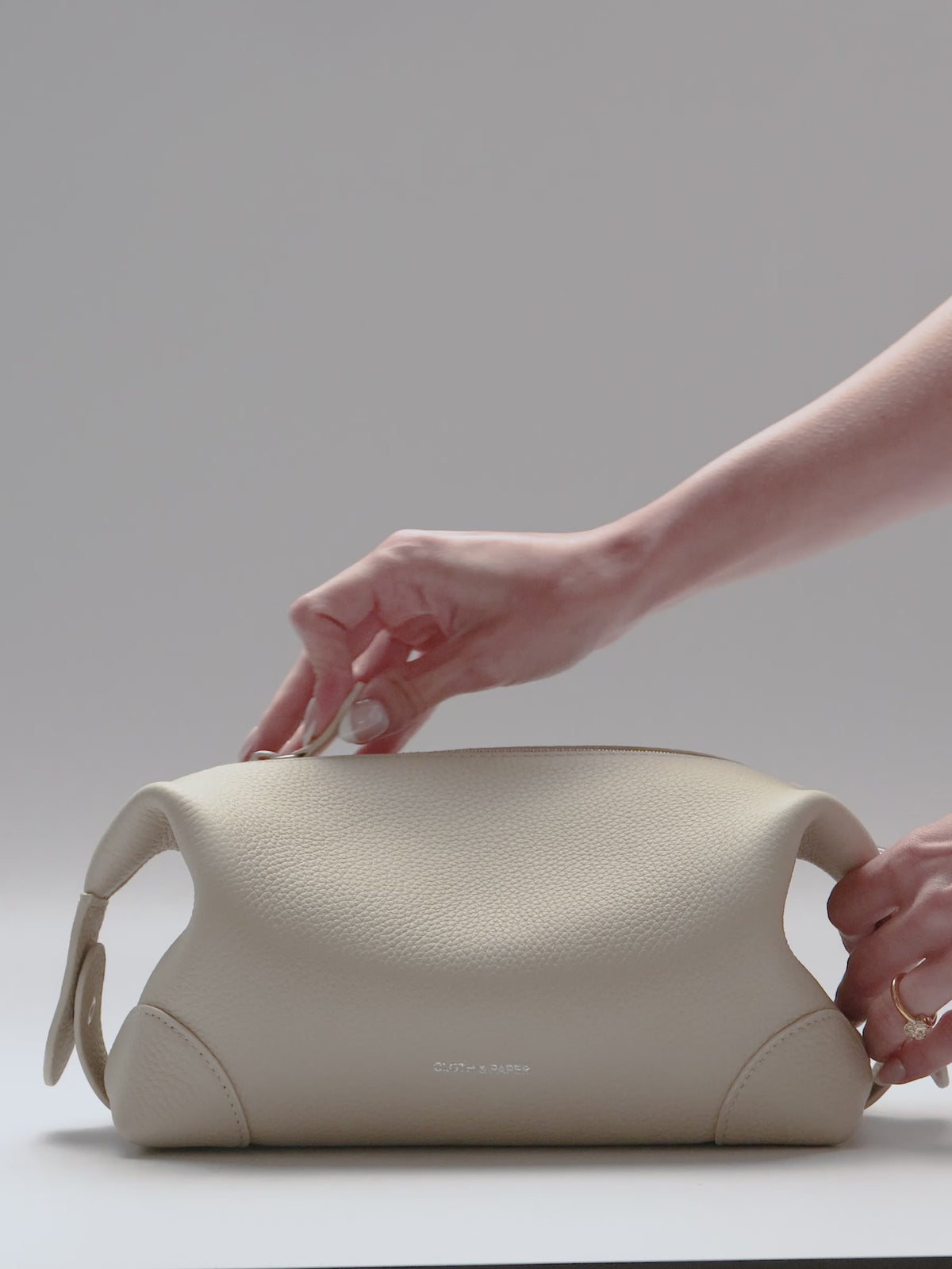 Woman using the Folded Form Pouch in the color Ristretto, an off-white, with planners and accessories