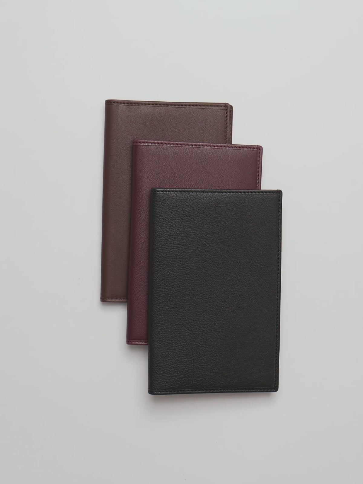 Woman opening and using pockets in leather Nomada Wallet in brown, burgundy, and brown.